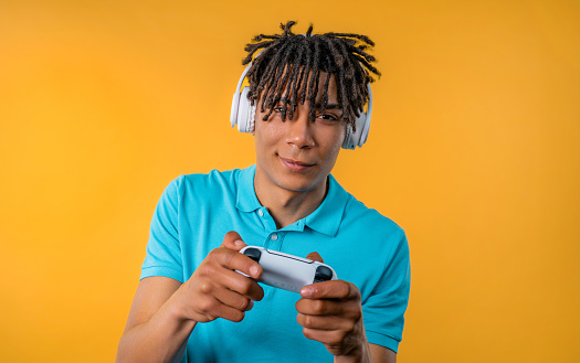 Handsome young man playing video exciting game on Tv with joystick isolated on yellow studio background. Using modern technology. High quality photo