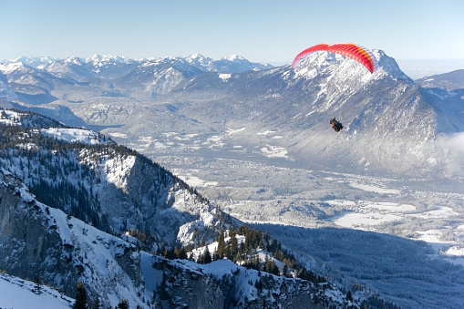 Hochalm, Austria- 13 January 2024: A paraglider flying over a winter landscape in Salzburg, Austria. He started from the mountain station Untersberg, Salzburg.