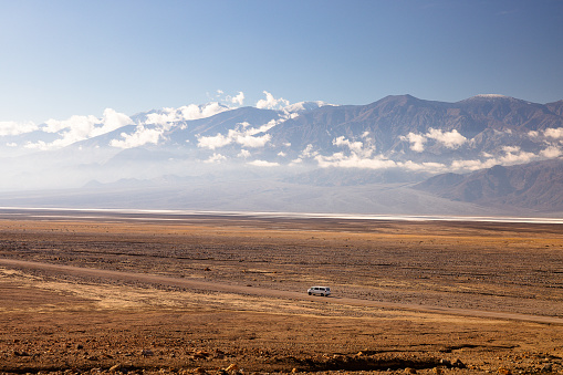 Desert vastness along Gower Gulch with the iconic Telescope Mountains as a backdrop. Alone white camper adds a touch of solitude to the expansive beauty of Death Valley's desert expanse