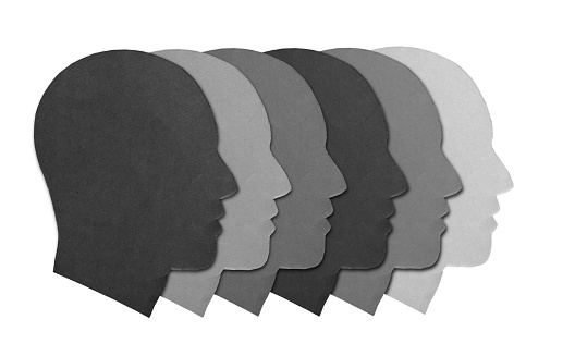 Group of faces of different shades of gray in profile, representing multiracial diversity.