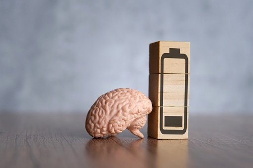 Closeup image of brain and wooden blocks with low energy battery icon. Exhausted, tired and burnout concept.