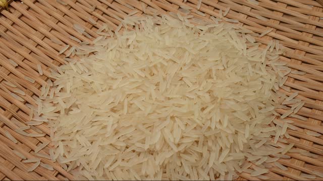 Uncooked raw white long grain rice pour drop fall on bamboo tray spin rotate pan