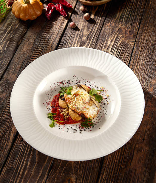 istock Baked eggplant roll with cheese and tomatoes, elegantly plated on a white dish 1942541565
