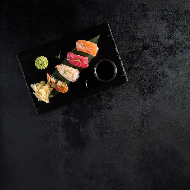Top view of classic nigiri sushi with salmon, tuna, eel, and shrimp on a black slate