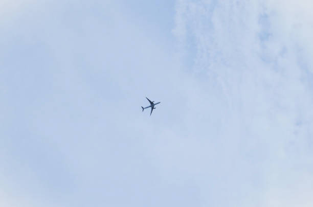 An airplane high in the sky among the thick clouds in the late afternoon