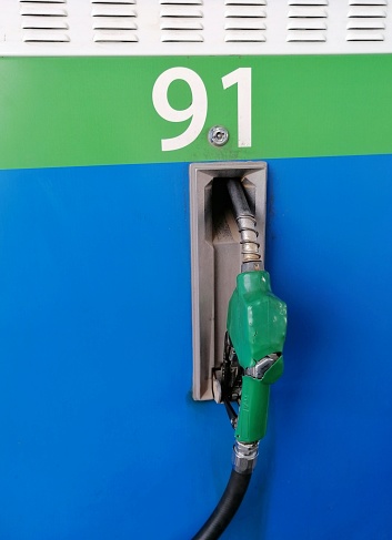 Old green standard petrol nozzle at gas station, 91 octane rating fuel type.