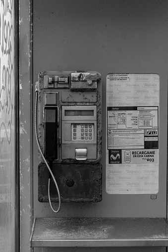 Vigo, Spain,: 08,21,2021: A booth with its old coin-operated telephone and the company sign and the call prices