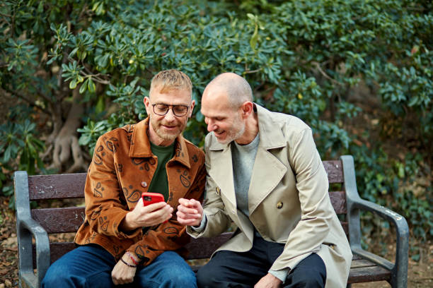 Smiling gay men looking at smart phone display together