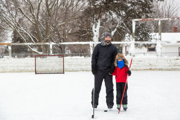 father & son at outdoor ice hockey rink - ice skating ice hockey child family imagens e fotografias de stock