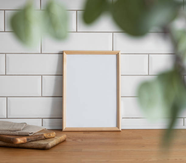istock A light frame with a blank canvas against a white tile wall and on a wooden tabletop 1942610148