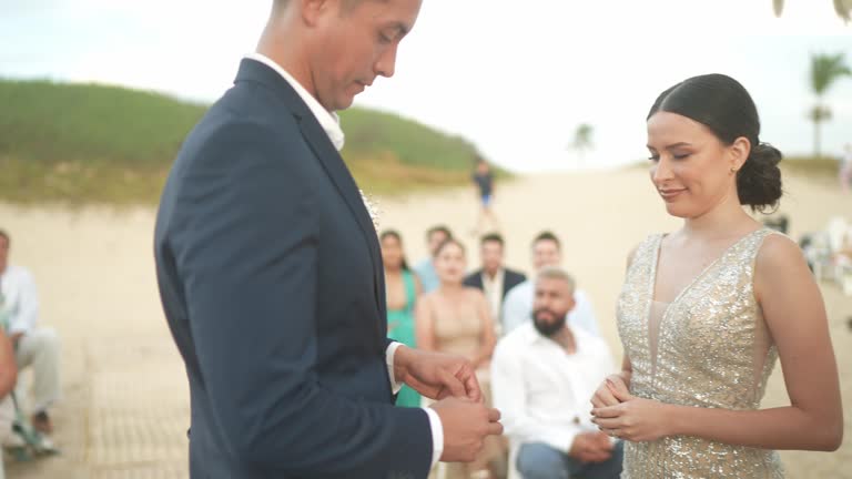 Young woman delivering the rings to groom and bride in wedding ceremony on the beach