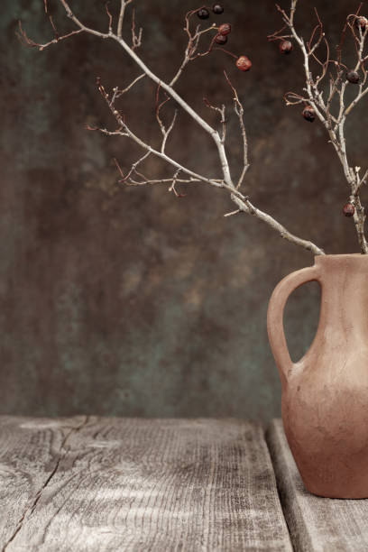 Jug with branches or twigs on a wooden table. Shallow depth of field