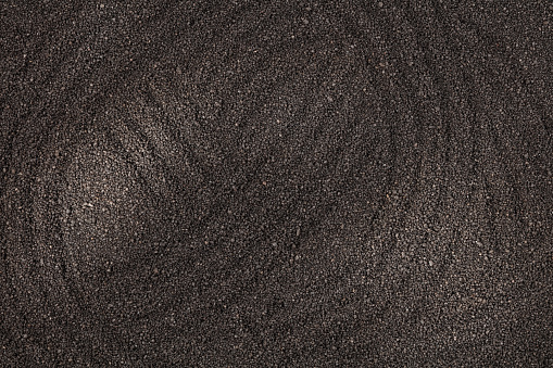 Black sand with traces and stripes may used as background. Top view