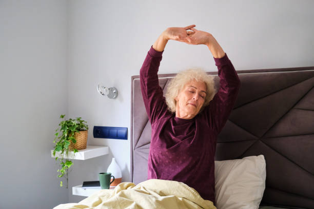 istock Old Latin woman stretching after restful sleep on her bed. 1942700613