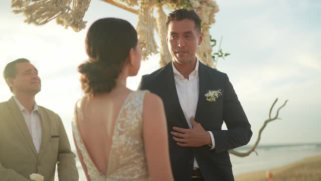 Groom talking with bride in wedding ceremony outdoors