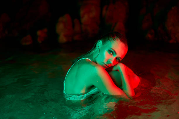 istock Woman immersed in water under red and green lights, night time, emotion expression, potential metaphor for struggle with depression or psychological distress. 1942725704