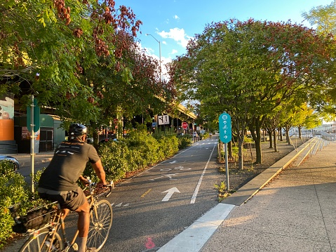 New York, NY USA : September 13, 2023 : Man biking on the Manhattan Waterfront Greenway by the West Harlem Piers along the Hudson River on a late summer evening in New York City