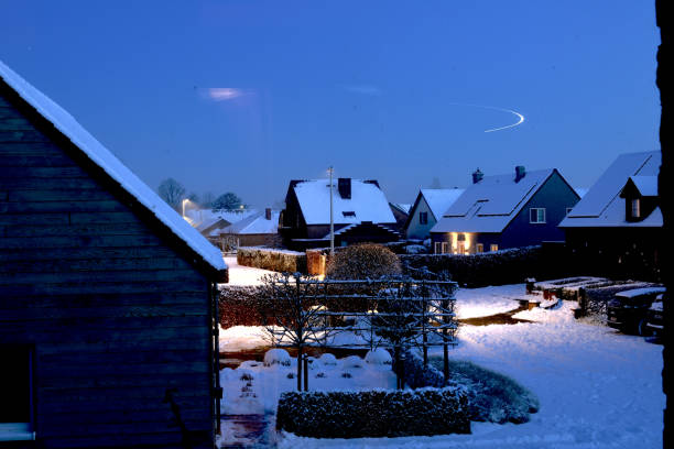 Leuven, Flemish-Brabant, Belgium-January 18, 2024: airplane trail light. High angle view a window first story. Snow falling at evening on a suburb of Leuven. A thick layer of snow lies on the roofs