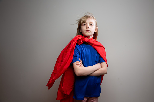 Blonde girl, 8 years old, wearing super hero costume and acting with arms crossed