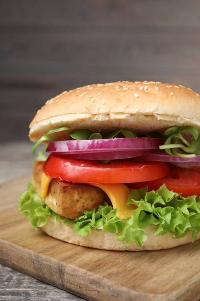 istock Delicious burger with tofu and fresh vegetables on table, closeup 1942776132