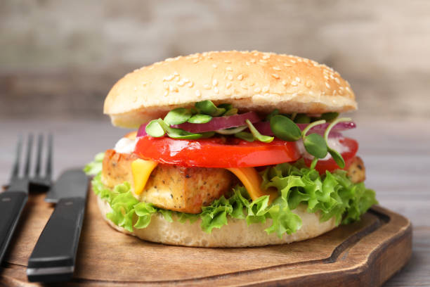 istock Delicious burger with tofu and fresh vegetables served on table, closeup 1942777090