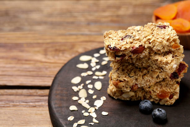 istock Stack of tasty granola bars on wooden table, closeup. Space for text 1942778151