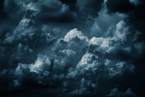 Black dark greenish blue sky with clouds. Dramatic background. Thunderstorm storm hurricane rain wind thunder lightning. Night moonlight. Creepy ominous frightening danger nightmare horror.Epic mystic.