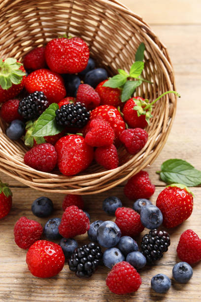 istock Wicker basket with many different fresh ripe berries on wooden table 1942805213