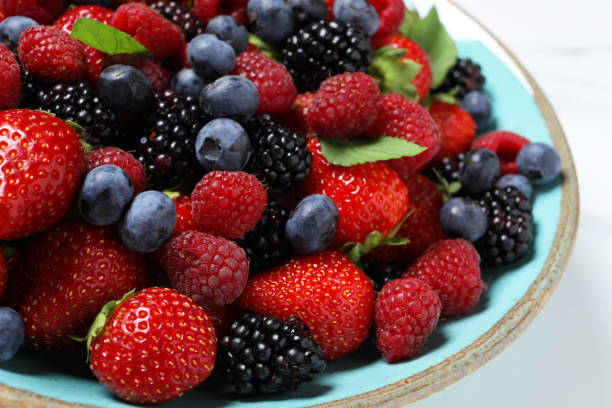 istock Many different fresh ripe berries in bowl on white table, closeup 1942805728
