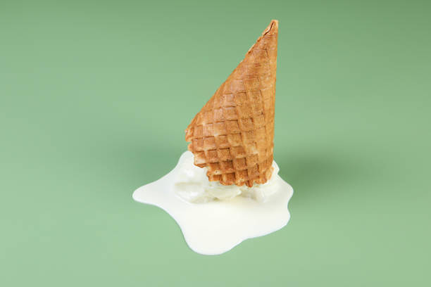 istock Melted ice cream and wafer cone on green background 1942805742