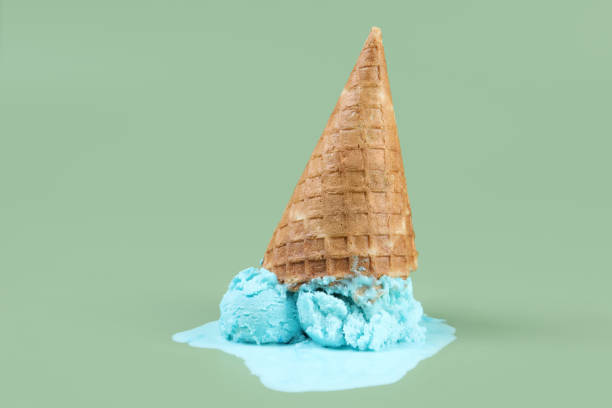 istock Melted ice cream and wafer cone on green background 1942805744