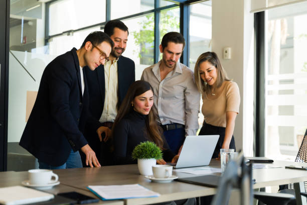 istock Group of five businesspeople looking at a laptop computer and reviewing a document 1942816889