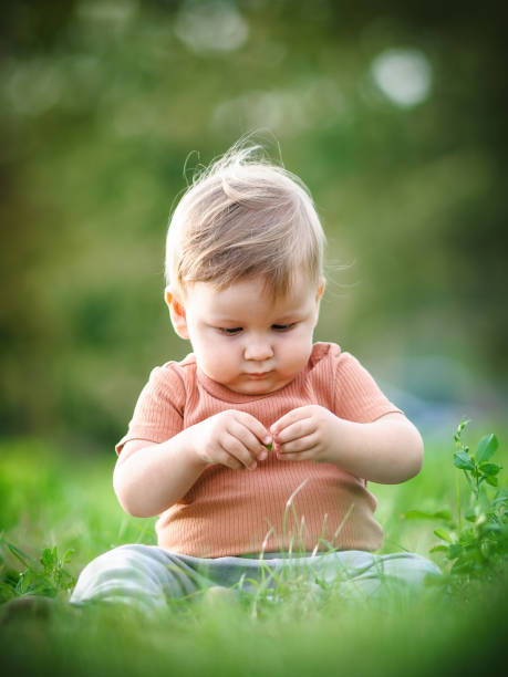 istock Cute baby having fun sitting on grass in sunshine day 1942827524