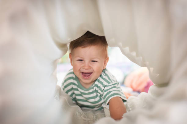 istock Cute happy laughing baby crawling through play tunnel 1942827959