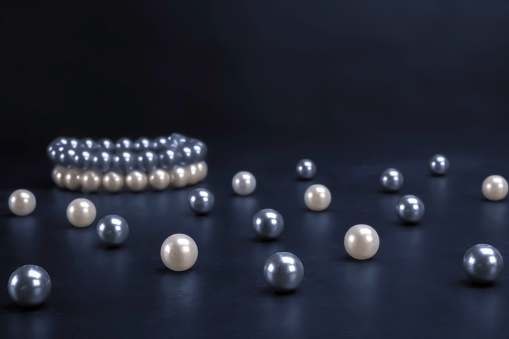 White and gray pearls and bracelets on black background. Fashion, accessory, jewelry, luxury, wealth concept.