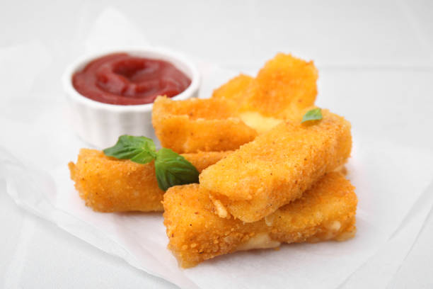 istock Tasty fried mozzarella sticks with basil leaves and ketchup on white table, closeup 1942829141