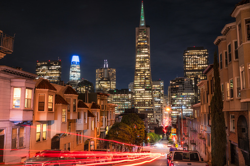 A long exposure at night as cars pass by, looking down the hill towards San Francisco's downtown cityscape.