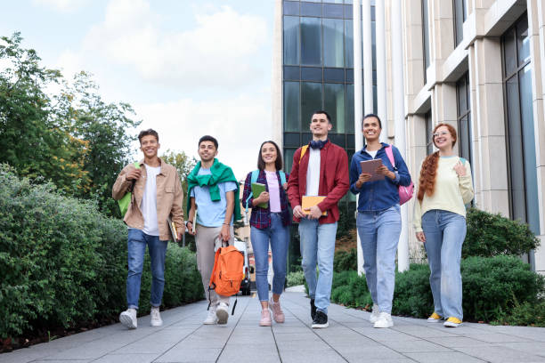 istock Group of happy students walking together outdoors, low angle view 1942846540