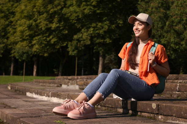 istock Happy young student with notebooks on steps in park, space for text 1942847119