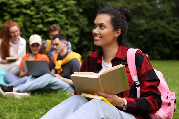 istock Students learning together in park. Happy woman studying with notebook on green grass, selective focus 1942848719