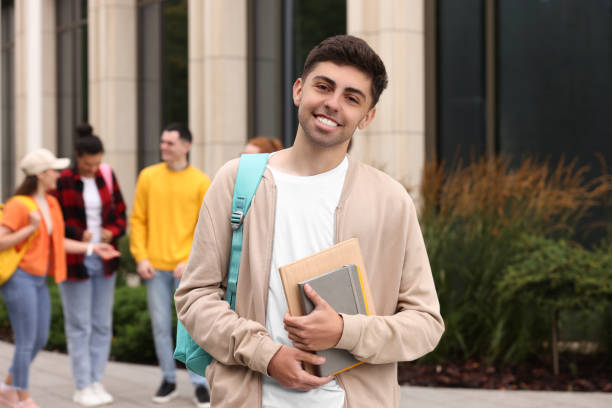 istock Students spending time together outdoors. Happy young man with notebooks, selective focus 1942848739