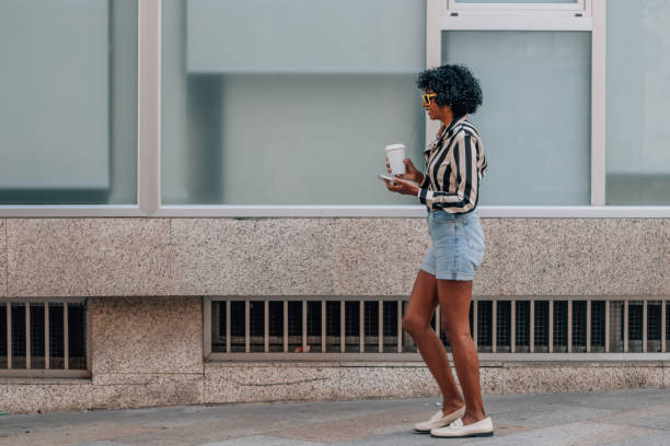 istock woman walking with mobile phone and cup 1942877734