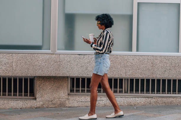 woman walking with mobile phone and cup