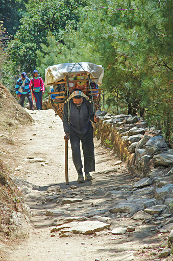 The mature adult sherpa porter carrying heavy sacks and boxes in the Himalayas at Everest Base Camp trek