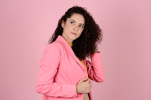 Woman with curly hair in photo shoot in photo studio with pink background. Confident & Diverse Hair Styling Portraits.