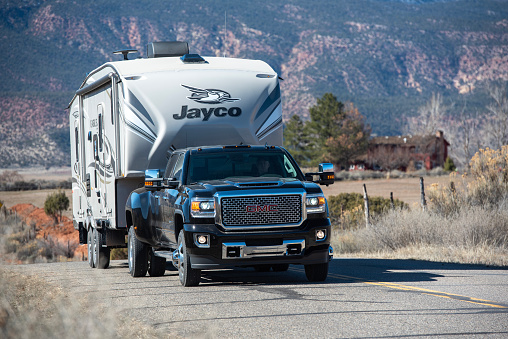 An RVer tows their 5th wheel travel trailer behind a pickup over a country road in northern Arizona.