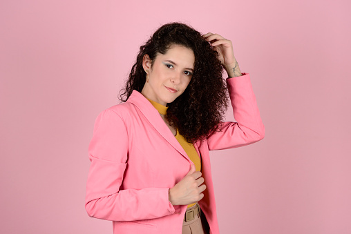 Woman with curly hair looking at camera during photo shoot in photo studio with pink background. Confident & Diverse Hair Styling Portraits.