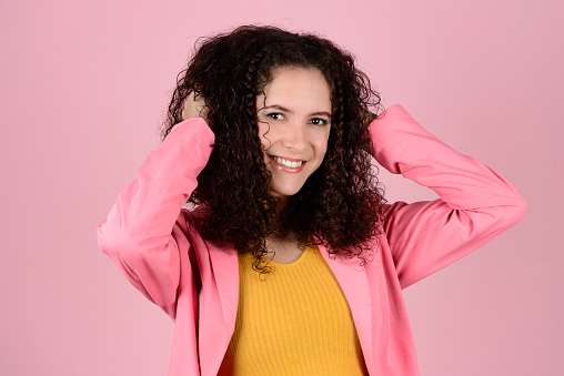 Woman stroking her curly hair during photo shoot in photo studio. Confident & Diverse Hair Styling Portraits