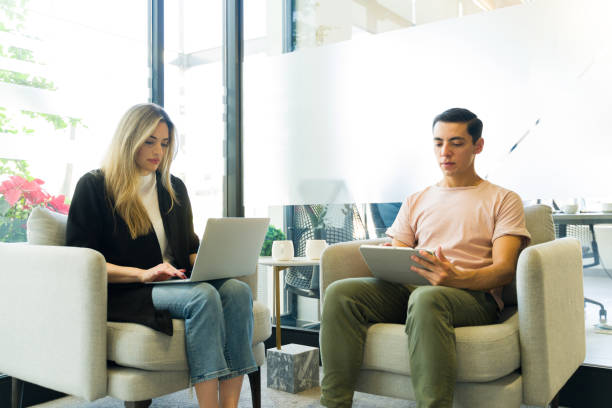 istock Two businesspeople in casual clothing working in comfortable chairs using their laptops 1942961851