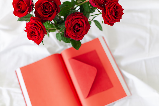 Book, roses, and orange paper in vase